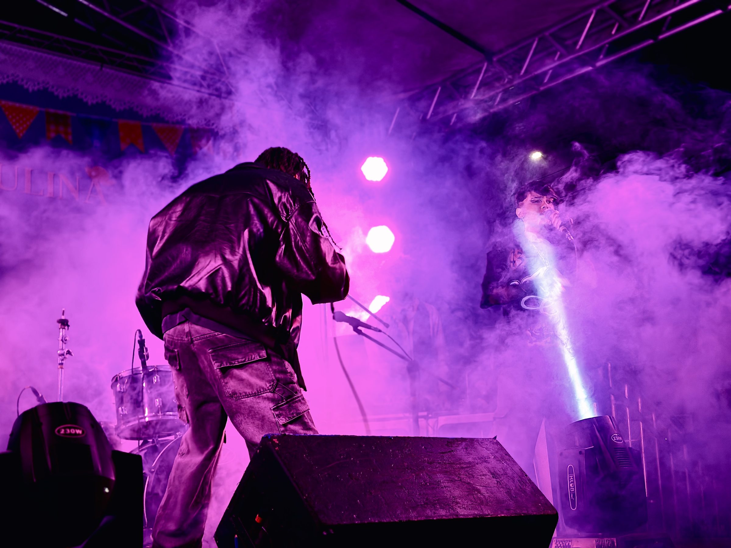 Performance de costas sob luz roxa e fumaça no show de 2026