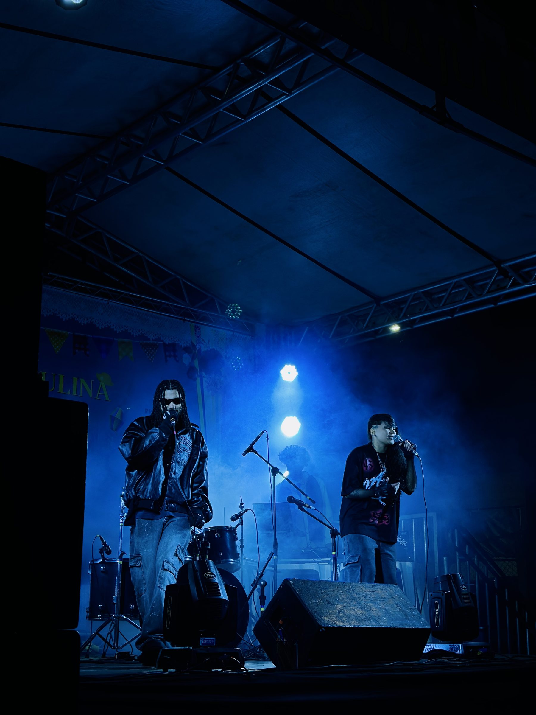 Dois performers no palco sob luz azul durante o show de 2026